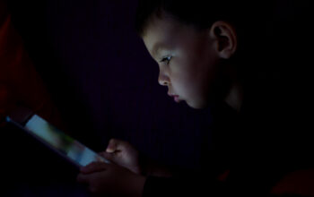 Cute kid with tablet in the dark.